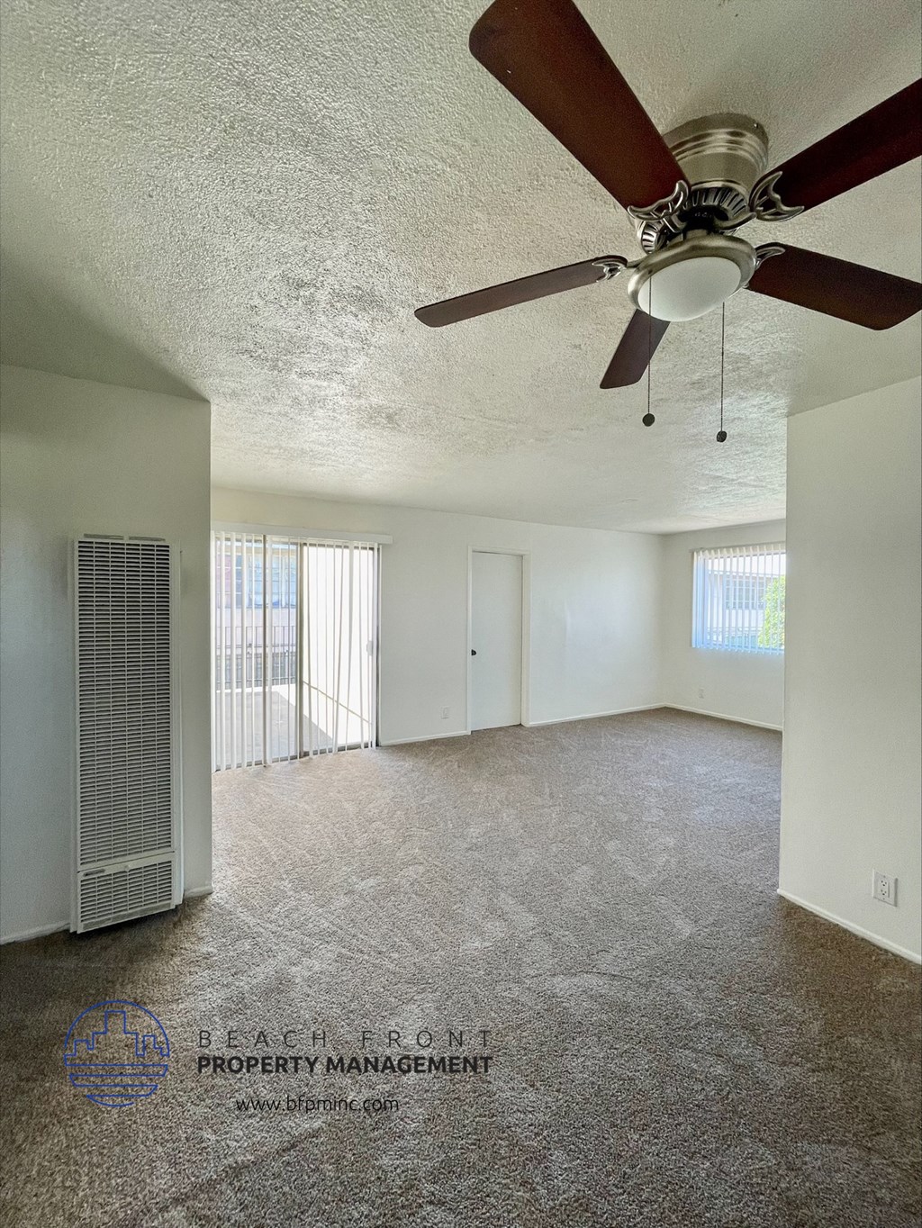 an empty living room with a ceiling fan